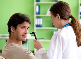 Female doctor checking patient's ear during medical examination