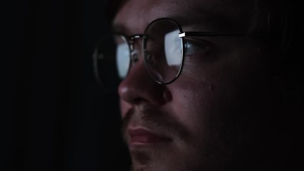 Business man, coder or programmer working late at night with laptop. Concept. Thoughtful focused guy in the dark with the computer screen reflected in his glasses.