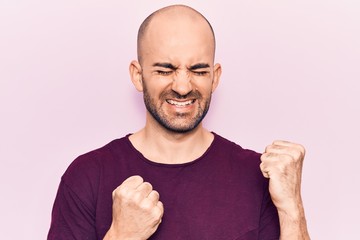 Young handsome bald man wearing casual t shirt celebrating surprised and amazed for success with arms raised and eyes closed