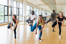 Pretty Active Young Woman Showing New Movement To Young People In Dance Class