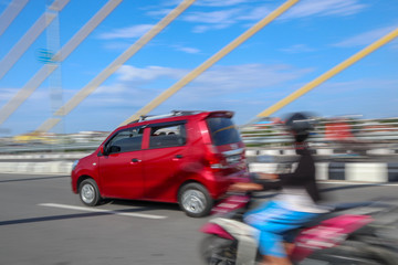 panning photo focus red car on the road and bridge