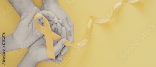 Fotomural adult and child hands holding yellow gold ribbon, Sarcoma Awareness, Bone cancer
