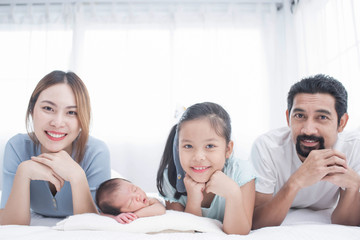 Poster - happy family mother, father and children laughing, playing and smiling in bed in bedroom at home. a young family with young children to bed in the bedroom.