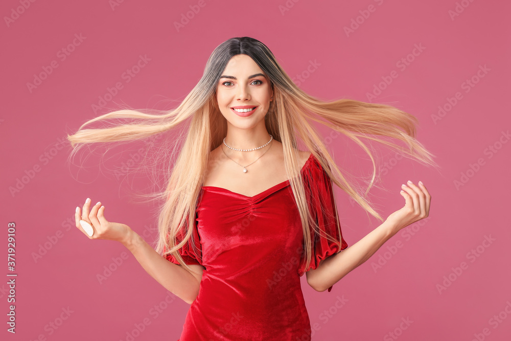 Beautiful young woman in wig on color background