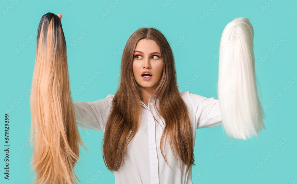 Beautiful young woman with different wigs on color background