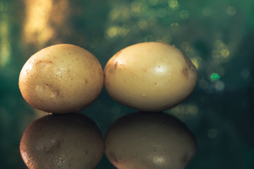 Poster - Fresh potato  on a black glass table and dark background.