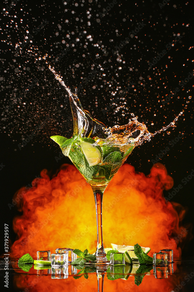 Glass of fresh mojito with splash on dark background