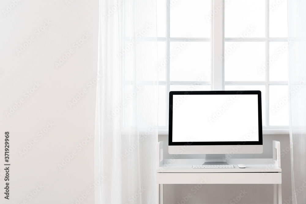 Modern PC monitor on table near window