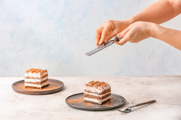 Woman preparing tasty tiramisu on table