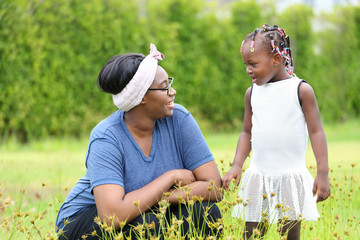 African American mother and daughter enjoy spending time together in the park at summer time with copy space