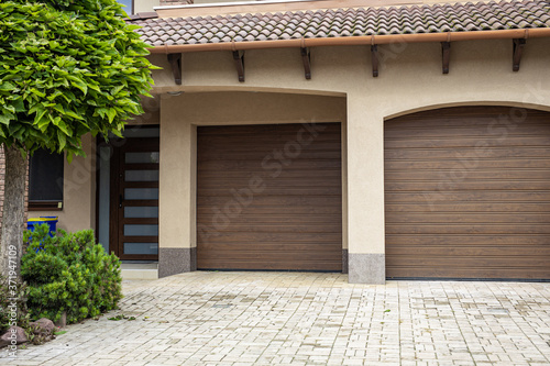 Fotomural Brick stone driveway double garage doors with green tree