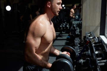 young athlete going to do exercises with heavy barbell, fit man doing deadlift exercise in sport gym