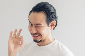 Funny grinning smile face of Asian man in white t-shirt and grey background.