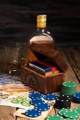 Banknotes next to poker chips, bottle, whiskey glass