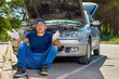 © JENOCHE - Upset driver man in front of old automobile broken car in city road.