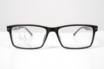 close up of broken black glasses on a white background. vision examination and repair.