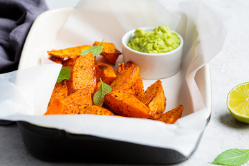 Wall Mural - Baked sweet potato wedges with guacamole. Healthy vegan food concept.