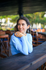 Wall Mural - Close up portrait of beautiful woman with jewelry. Smiling Caucasian woman wearing blue dress and sitting in the beach bar. Travel lifestyle.