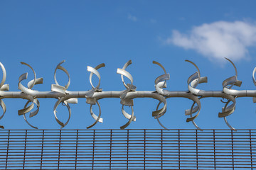 Restricted area.  Close up of barbed wire security fence against a blue sky