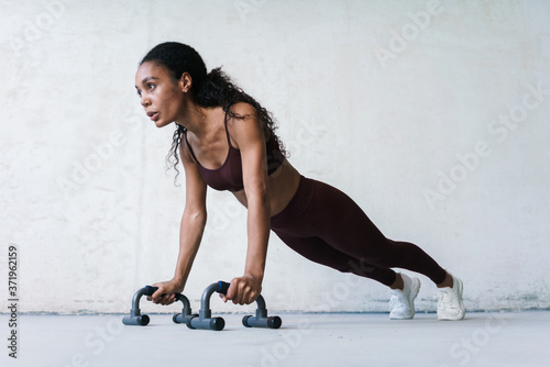 Photo of african american sportswoman working out with push-up stops