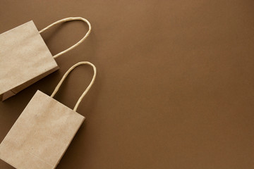 Two craft brown paper shopping bags isolated on brown background, copy space.