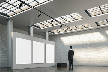 Poster - Businessman standing in modern gallery interior with three empty billboards