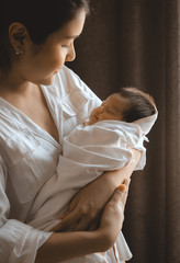 Wall Mural - close-up young woman holding a newborn baby in her arms.