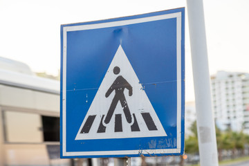 Worn out candid pedestrain cross walk sign on the road side.