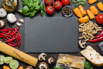 Wall Mural - Italian food ingredients over black stone background. 