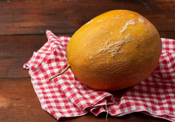 whole round yellow ripe melon on a browm wooden background