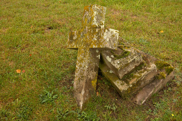 Aged broken Cross grave stone in old English graveyard