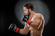 © fusssergei - A man in Boxing gloves. A man Boxing on a black background. The concept of a healthy lifestyle