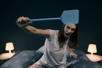 Wall Mural - Angry woman killing mosquitoes with a fly swatter