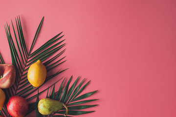 Wall Mural - Summer tropical composition made with fresh fruit and green palm leaves on pastel pink background. Flat lay food.