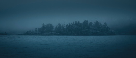 silhouette of a forested island in the fog. panoramic image.