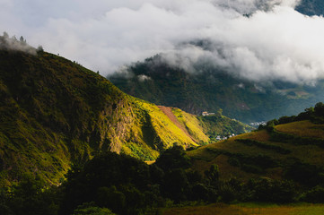 Small village overwhelmed by high Himalayas and clouds. Tawang, India.