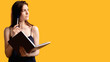 © golubovy - Thinking problem. Puzzled woman with notebook. Isolated on orange free space. Question concept. Guess idea. Payment planning