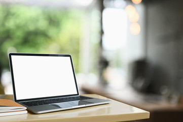 Poster - Workspace computer laptop with a white blank screen is putting on a wooden table in the living room.