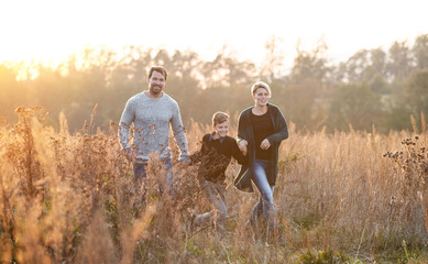 Wall Mural - Beautiful young family with small son on a walk in autumn nature.