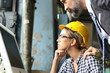 © Stella - Young beautiful woman industrial engineer worker wearing helmet and safety glasses discussing, using computer with businessman, people work at manufacturing plant industry factory, boss and secretary