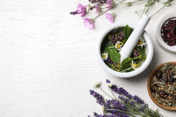 Poster - Mortar with healing herbs and pestle on white wooden table, flat lay. Space for text