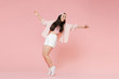 © ViDi Studio - Full length portrait of funny young asian girl in casual clothes, cap isolated on pastel pink background studio. People lifestyle concept. Mock up copy space. Dancing spreading hands standing on toes.