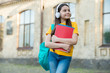 © be free - her favorite melody. back to school. teen girl listen audio book. child with notebook in schoolyard. happy kid holding folder. small girl wear earphones outdoor. school education in modern life