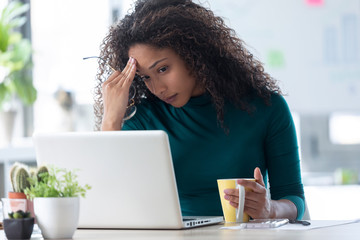 Wall Mural - Exhausted young woman with headache working with laptop at the office.