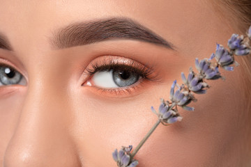 Eyes and eyebrows close-up.Portrait of a beautiful teenage girl with beautiful makeup, extended long eyelashes and healthy clean skin.Near the eyes is branch of lavender.Makeup and cosmetology concept