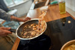 Close up of hand of man tossing shrimp with garlic and onion in the frying pan. Cook preparing dish with seafood. Mediterranean cuisine concept