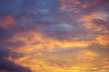 Cloudy Sky At Sunset. Dark Purple-yellow Natural Background Or Wallpaper. The Rays Of The Setting Sun Effectively Illuminate The Clouds. Beautiful And Dramatic Evening Skies