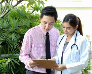 South East Asian young Malay Chinese man woman medical doctor talking discussing outdoor