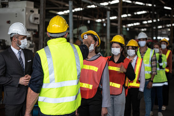 factory manager and staff checking fever digital thermometer for industrial workers before working i