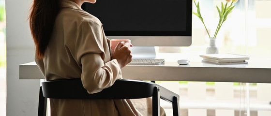 Wall Mural - Close up image of business woman holding coffee cup in the office.